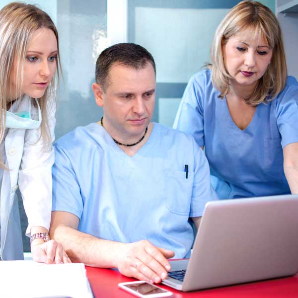 Dentists configuring Dentimax dental software around a laptop